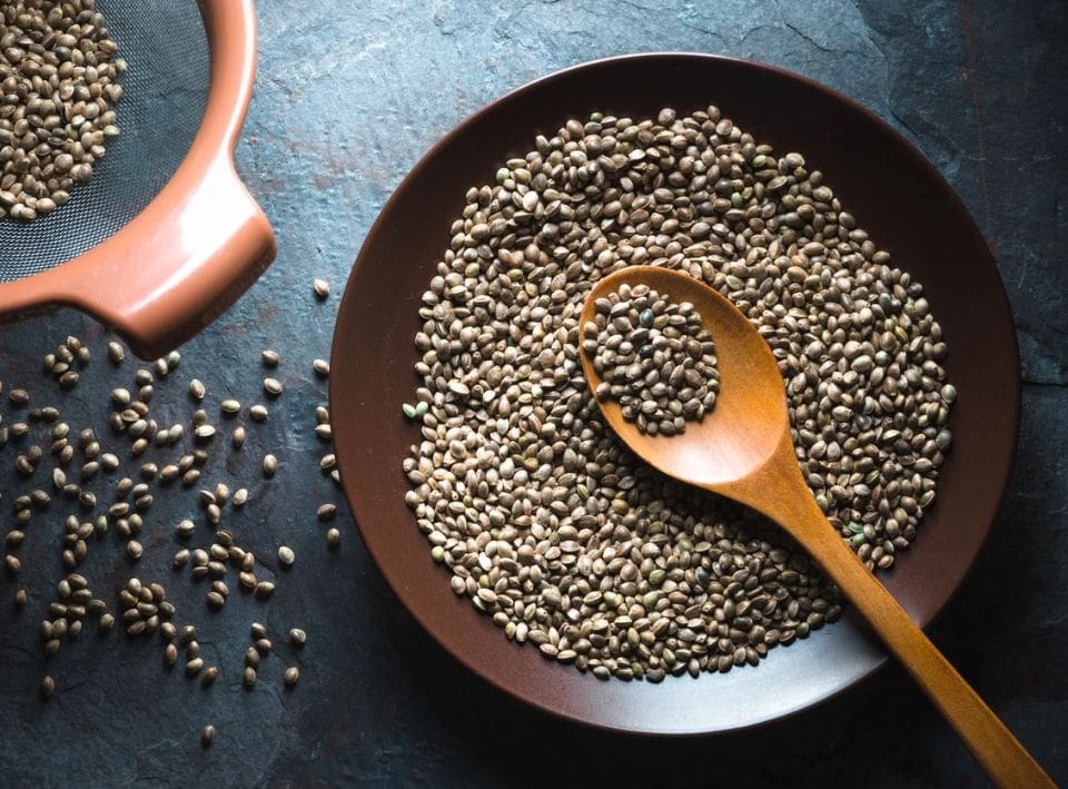 A bowl of seeds and wooden spoon on the table.