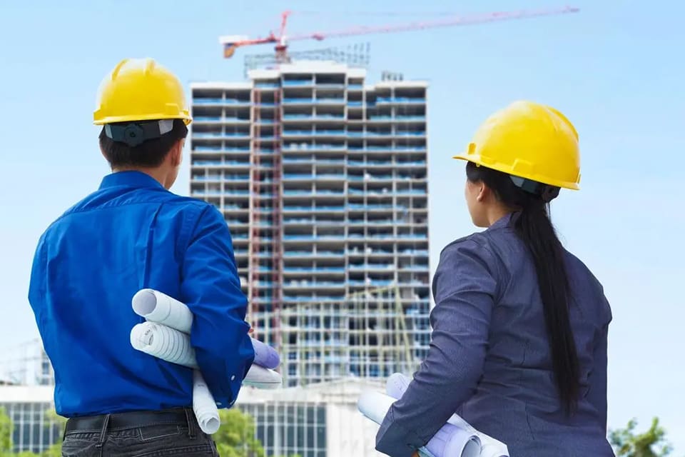 Two people wearing hard hats looking at a building