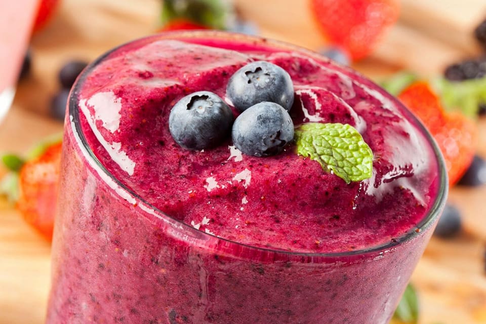 A close up of some berries and broccoli in a smoothie